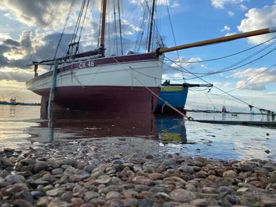 a boat is docked on a rocky shore at Oyster Lodge in West Mersea