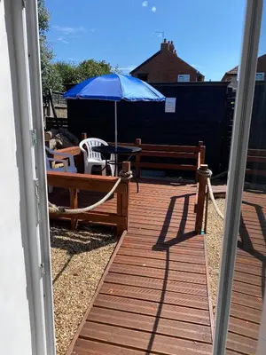 a patio with a table and a blue umbrella at Oyster Lodge in West Mersea