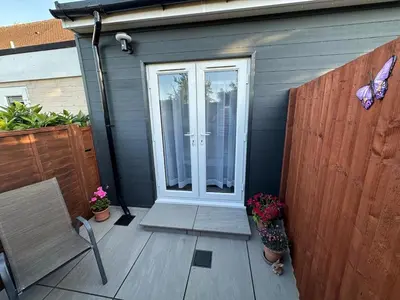 a patio with a door and a bench and flowers at Little side house in Cambridge in Trumpington
