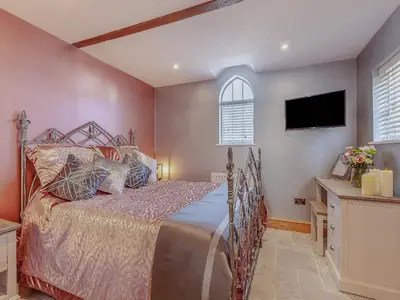 a bedroom with a bed and a tv on the wall at The School House Cottage in Bradwell on Sea