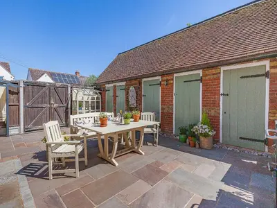 a patio with a table and chairs and a building at The School House Cottage in Bradwell on Sea