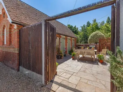 an open gate to a patio with a bench at The School House Cottage in Bradwell on Sea
