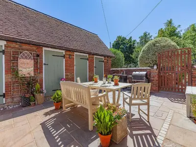 a patio with a table and chairs in a backyard at The School House Cottage in Bradwell on Sea