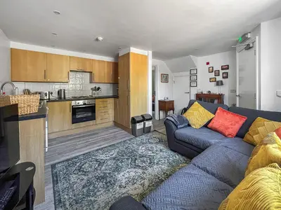 a living room with a couch and a kitchen at Moglett Cottage in Fincham