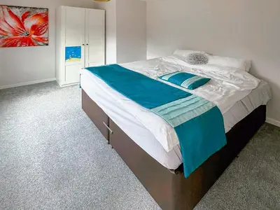 a bedroom with a large bed with blue and white sheets at Spring Vale Bungalow in Colchester