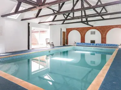 an indoor swimming pool with blue water at The Farmhouse - Uk48228 in Tibenham