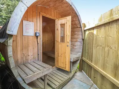 a wooden outhouse with a door and a bench at The Farmhouse - Uk48228 in Tibenham
