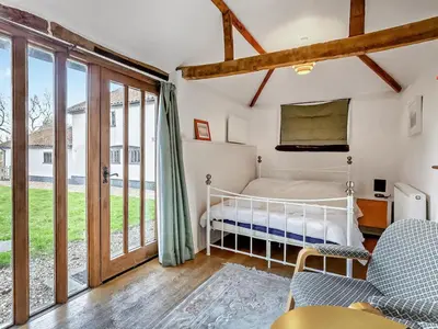 a bedroom with a bed and sliding glass doors at The Farmhouse - Uk48228 in Tibenham