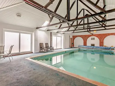 a large swimming pool in a large room with windows at The Pool House - Uk48229 in Tibenham
