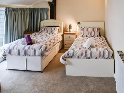 two beds sitting next to each other in a bedroom at The Pool House - Uk48229 in Tibenham
