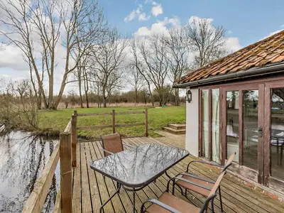 a patio with a table and chairs on a wooden deck at Pond View Cottage - Uk48230 in Tibenham
