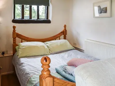 a bed with a wooden frame and pillows on it at The Retreat - Uk48231 in Tibenham