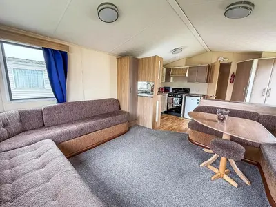 a living room with a couch and a table at Great 8 Berth Caravan With Unlimited Wi-Fi At Seawick Holiday Park, Ref 27213Sw in Clacton-on-Sea