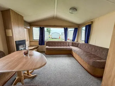 a living room with a couch and a table at Great 8 Berth Caravan With Unlimited Wi-Fi At Seawick Holiday Park, Ref 27213Sw in Clacton-on-Sea