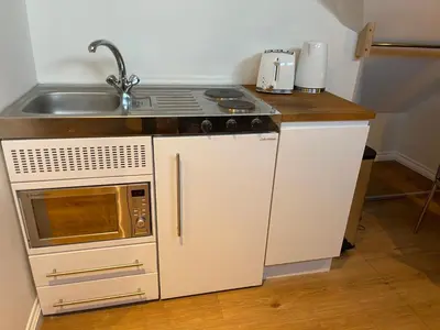 a small kitchen with a sink and a stove at Cosy Loft Retreat off Vibrant Mill Road - walk to station and City centre in Cambridge