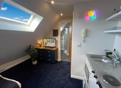 a bathroom with a sink and a tv in a room at Cosy Loft Retreat off Vibrant Mill Road - walk to station and City centre in Cambridge
