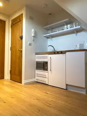 a kitchen with white appliances and a wooden floor at Cosy Loft Retreat off Vibrant Mill Road - walk to station and City centre in Cambridge
