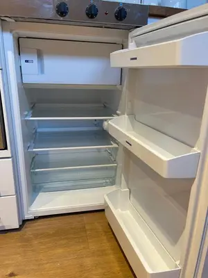 an empty refrigerator with its door open in a kitchen at Cosy Loft Retreat off Vibrant Mill Road - walk to station and City centre in Cambridge