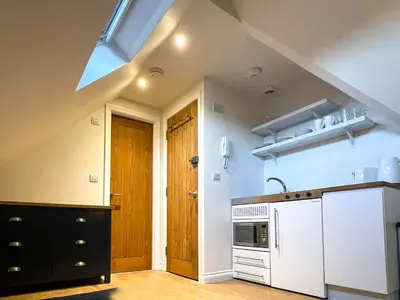 a kitchen with white appliances and a wooden door at Cosy Loft Retreat off Vibrant Mill Road - walk to station and City centre in Cambridge