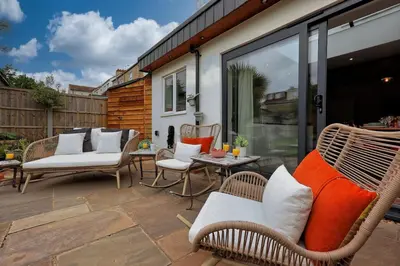 a patio with wicker chairs and a table at Beautiful 5 bed house, relaxing garden and driveway parking 10 min to the beach in Southend-on-Sea
