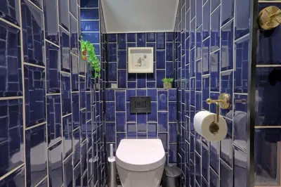 a bathroom with blue tiled walls and a toilet at Beautiful 5 bed house, relaxing garden and driveway parking 10 min to the beach in Southend-on-Sea