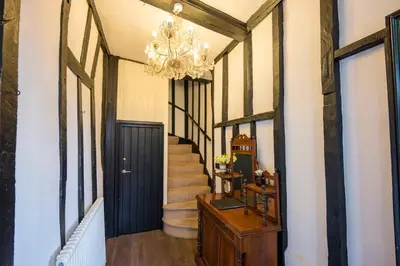 a hallway with a black door and a chandelier at Cotton Room, The Merchant House, Ipswich in Ipswich