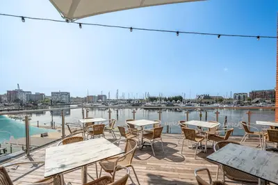 a patio with tables and chairs overlooking a marina at Cotton Room, The Merchant House, Ipswich in Ipswich