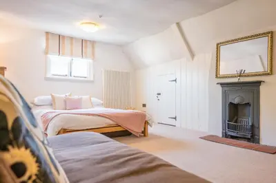 a bedroom with two beds and a fireplace at Merchant Quarters, The Merchant House, Ipswich in Ipswich