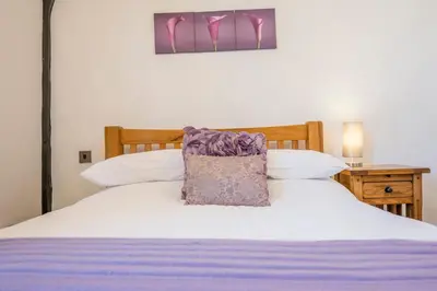 a bed with a purple pillow on top of it at Silk Room, The Merchant House, Ipswich in Ipswich