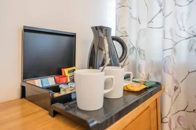 two mugs sitting on a table next to a tv at Silk Room, The Merchant House, Ipswich in Ipswich