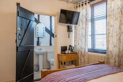a bedroom with a bed and a toilet and a television at Silk Room, The Merchant House, Ipswich in Ipswich