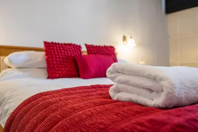 a bed with a red and white blanket and pillows at Wool Room, Merchant House, Ipswich in Ipswich