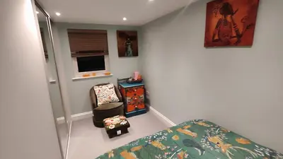 a bedroom with a bed and a chair and a television at Crystalsspace in Braintree