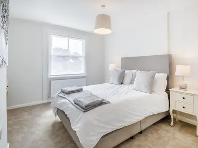 a white bedroom with a large bed with white pillows at Courtyards in Diss