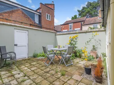 a patio with a table and chairs in a backyard at Courtyards in Diss