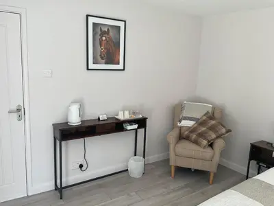 a bedroom with a table and a chair and a picture at The Meadow Garden Guest Room in Newmarket