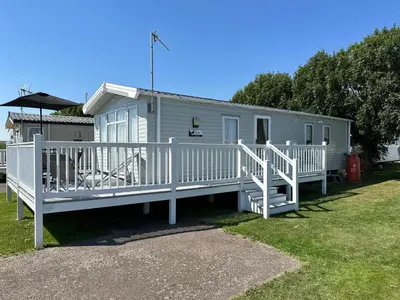 a mobile home with a porch and white railing at Your Seaside Escape at St Osyth Modern caravan with decking and wifi and parking Nr to Clacton on Sea in Saint Osyth
