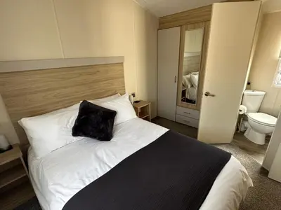 a bedroom with a bed with a black pillow on it at Your Seaside Escape at St Osyth Modern caravan with decking and wifi and parking Nr to Clacton on Sea in Saint Osyth