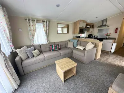 a living room with a couch and a kitchen at Your Seaside Escape at St Osyth Modern caravan with decking and wifi and parking Nr to Clacton on Sea in Saint Osyth