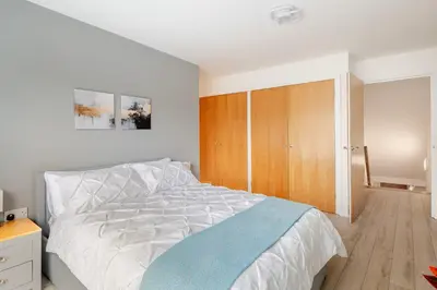 a bedroom with a bed and a wooden cabinet at Stunning 2 Bedroom Flat with Charming Patio in Cambridge