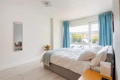 a bedroom with a bed with blue curtains and a window at Stunning 2 Bedroom Flat with Charming Patio in Cambridge