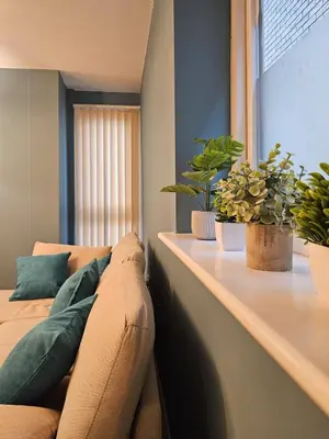 a living room with a couch and two potted plants at Stunning 2 Bedroom Flat with Charming Patio in Cambridge