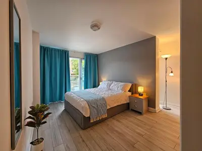 a bedroom with a bed with blue curtains at Stunning 2 Bedroom Flat with Charming Patio in Cambridge
