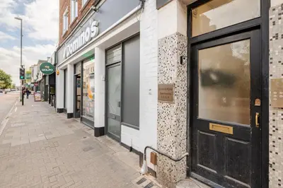a building with a black door on a street at Stunning 2 Bedroom Flat with Charming Patio in Cambridge