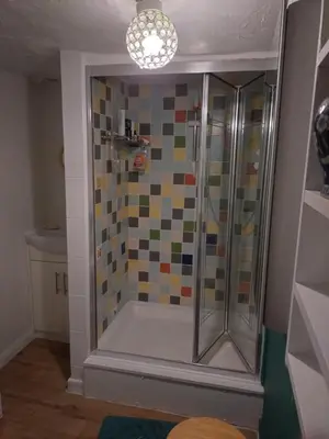 a bathroom with a shower with a tiled wall at The Old Sweet Shop in Harwich