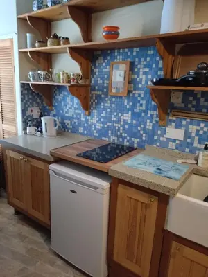 a kitchen with wooden cabinets and blue tiles at The Old Sweet Shop in Harwich