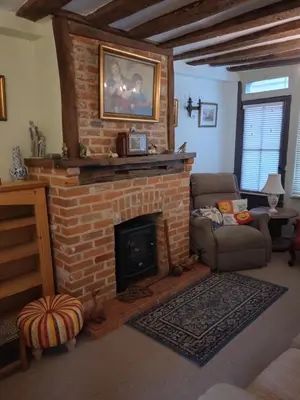 a living room with a brick fireplace and a chair at The Old Sweet Shop in Harwich