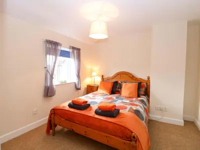 a bedroom with a bed with orange pillows on it at Honeysuckle Cottage in Swaffham
