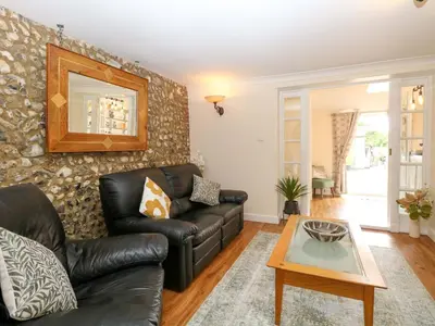 a living room with a leather couch and a table at Honeysuckle Cottage in Swaffham