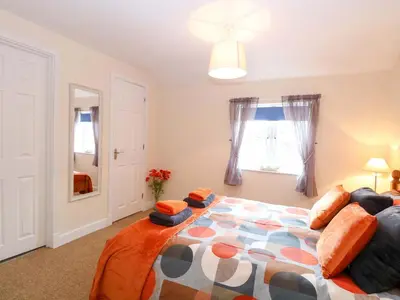 a bedroom with a large bed and a window at Honeysuckle Cottage in Swaffham